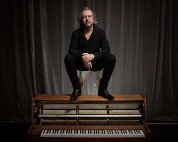 Marcus Schinkel auf dem Klavier sitzend | © Lars Figge